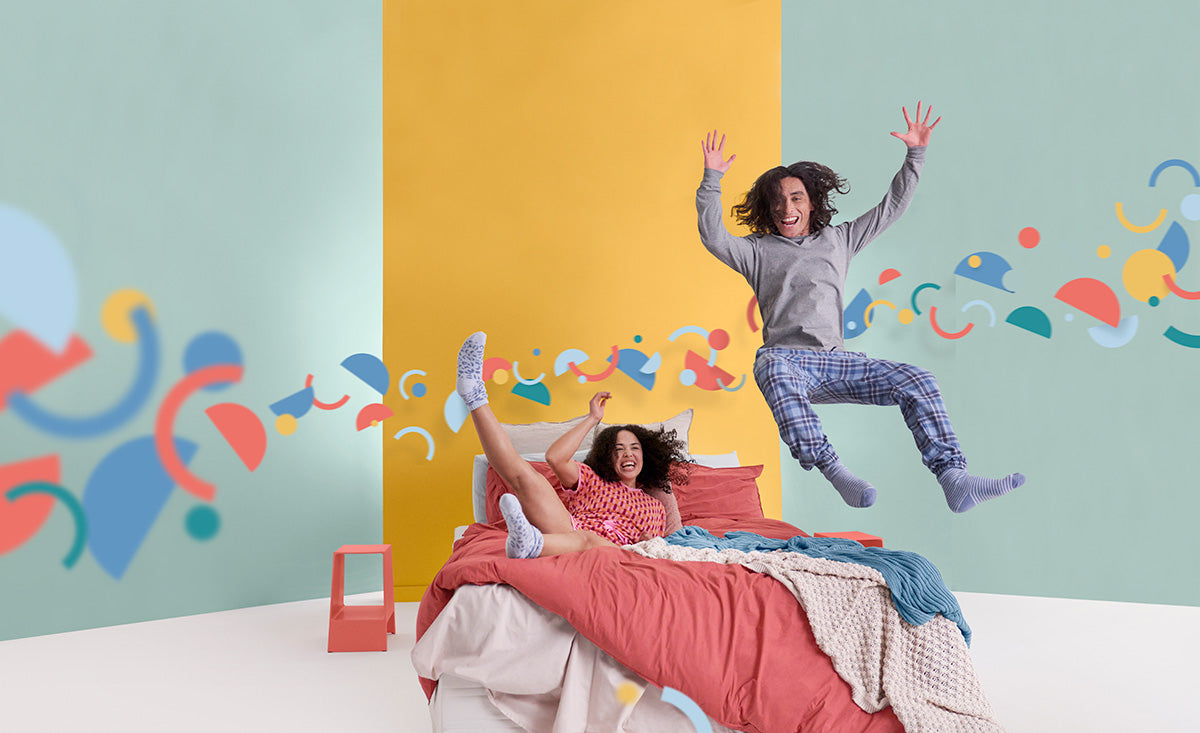 Joyful Couple Jumping onto Joy Mattress - Embracing Fun and Comfort