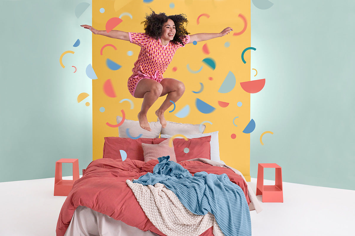 Joyful Woman Jumping on Joy Mattress - Experience Happiness and Comfort